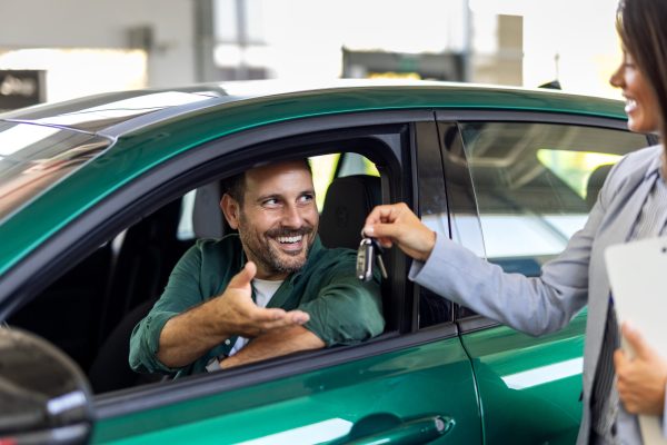 Happy businessman buying new and luxury car. Beautiful female dealer helps him to make right decision. Man Driver Taking Keys From Manager While Sitting In Rental Auto,